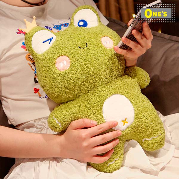 A girl is sitting on a couch holding a stuffed frog.
